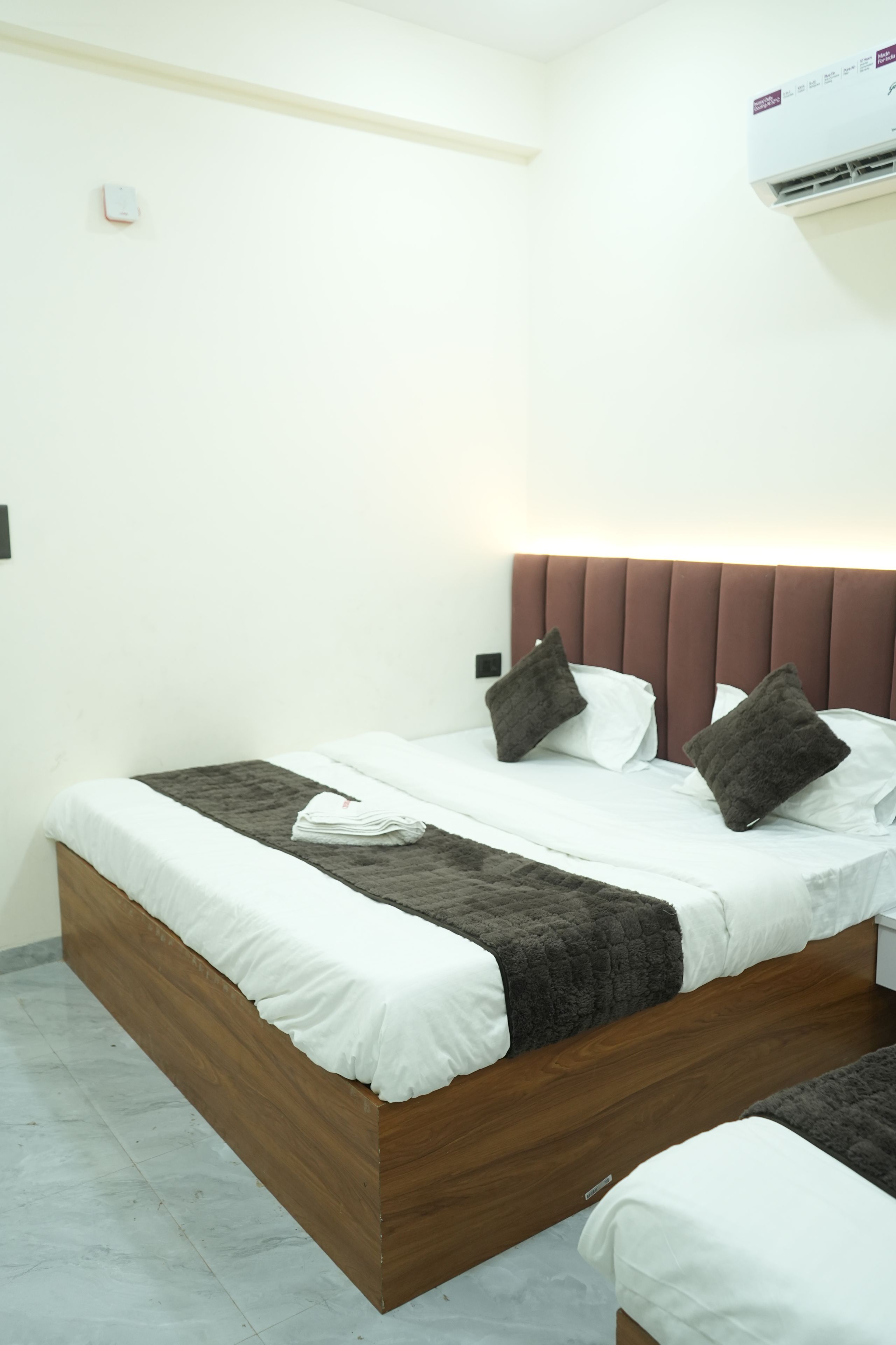 A neatly made bed with a wooden headboard, white bedding, and two dark pillows.