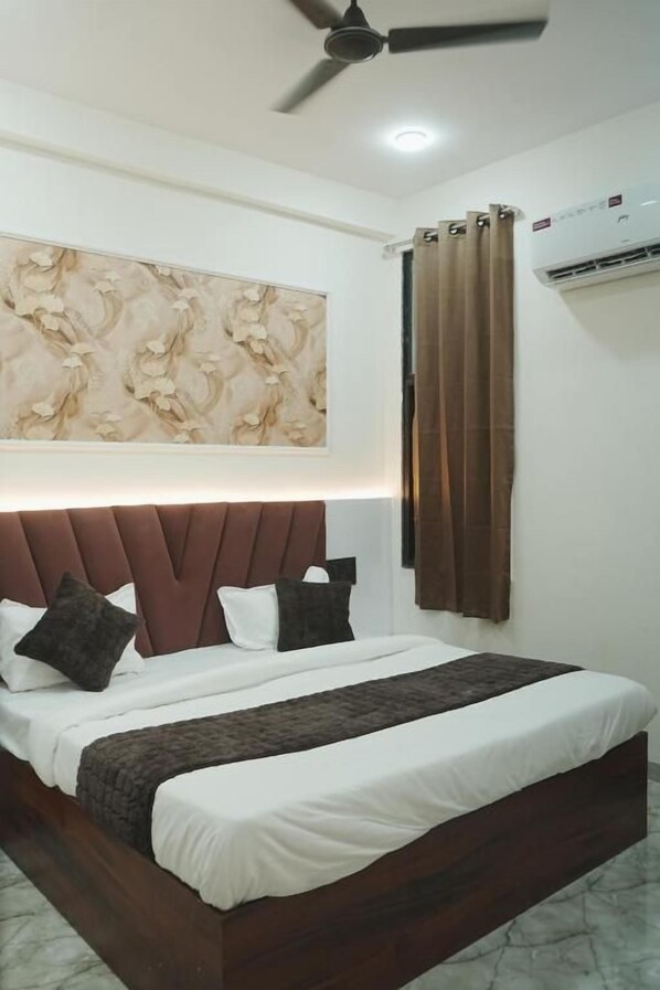 A hotel room with a bed, a ceiling fan, an air conditioning unit, and a wall-mounted artwork. - Hotel SP Residency (Indore)