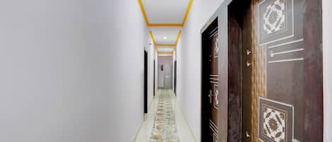 Un pasillo con piso estampado, una puerta con diseño geométrico y un número encima.