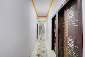A hallway with a patterned floor, a door with a geometric design, and a number above it. - Super Collection O Patna Airport (Danapur)
