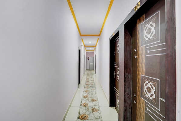 A hallway with a patterned floor, a door with a geometric design, and a number above it. - Super Collection O Patna Airport (Danapur)