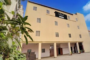 A multi-story building with a sign indicating it is a company-serviced hotel. - Super Collection O Patna Airport (Danapur)