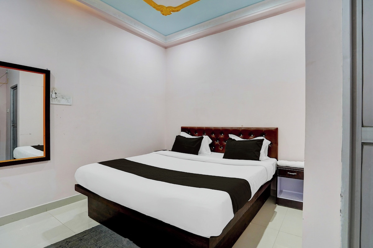 A hotel room with a bed, a nightstand, a mirror, and a ceiling with a decorative design.