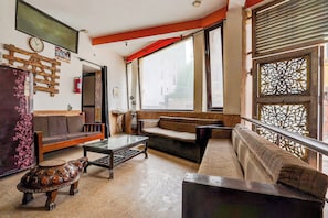 A living room with a sofa, a coffee table, and a decorative wooden stool. - Hotel O Sector 93 Noida (Noida)
