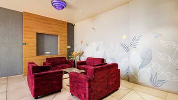 A reception area with red upholstered seating, a wooden accent wall, and a wall with a floral pattern.