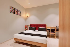 Un dormitorio con cama, escritorio y silla. Hay tres obras de arte enmarcadas en la pared.