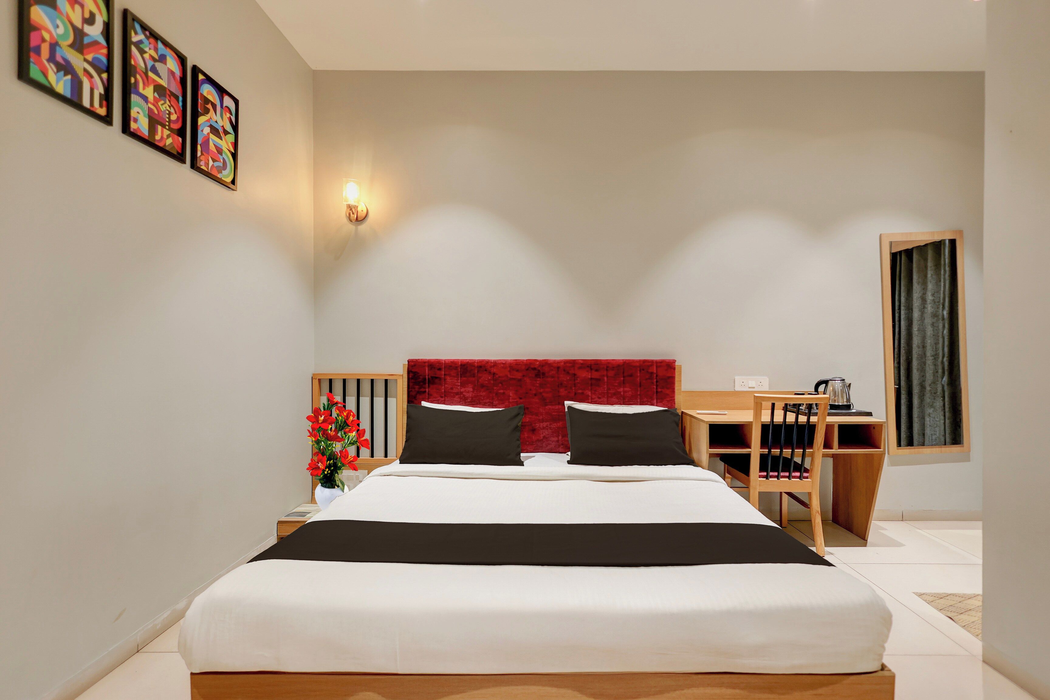 Una habitación de hotel moderna con una cama grande, un escritorio y un cabecero rojo.