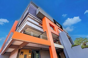 Un hotel de varios pisos con un diseño arquitectónico moderno, con balcones y una recepción.