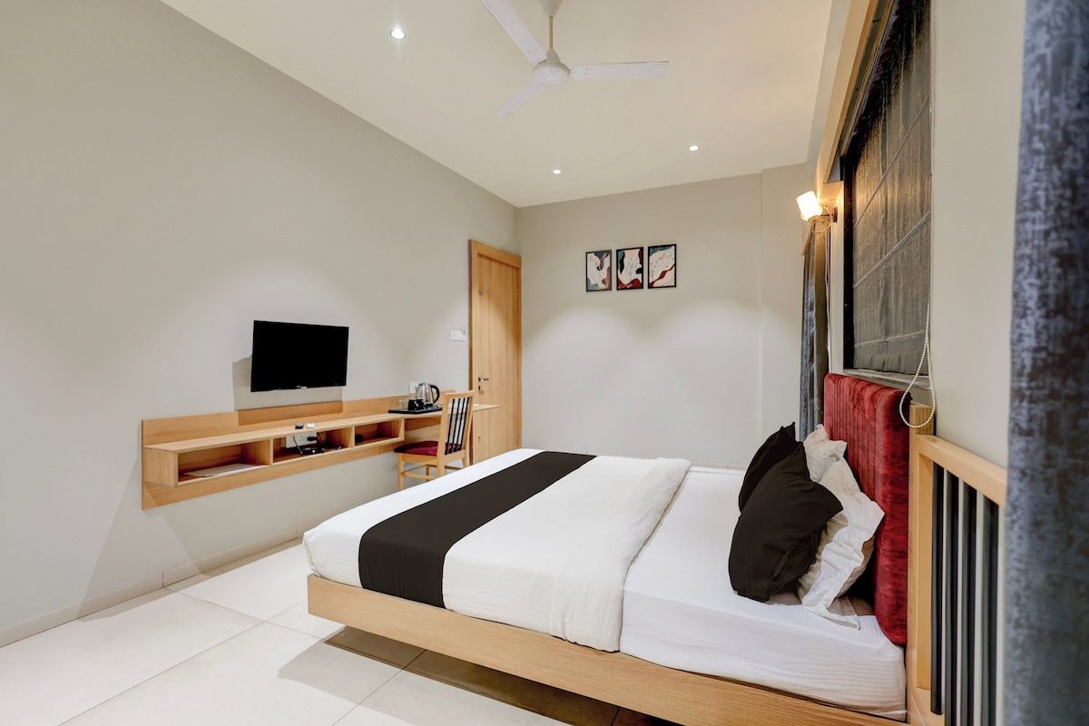 A modern bedroom with a bed, a TV mounted on the wall, a ceiling fan, and a window with curtains.