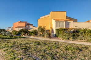 Un quartier résidentiel avec des maisons, un ciel dégagé et un chemin menant à une porte.