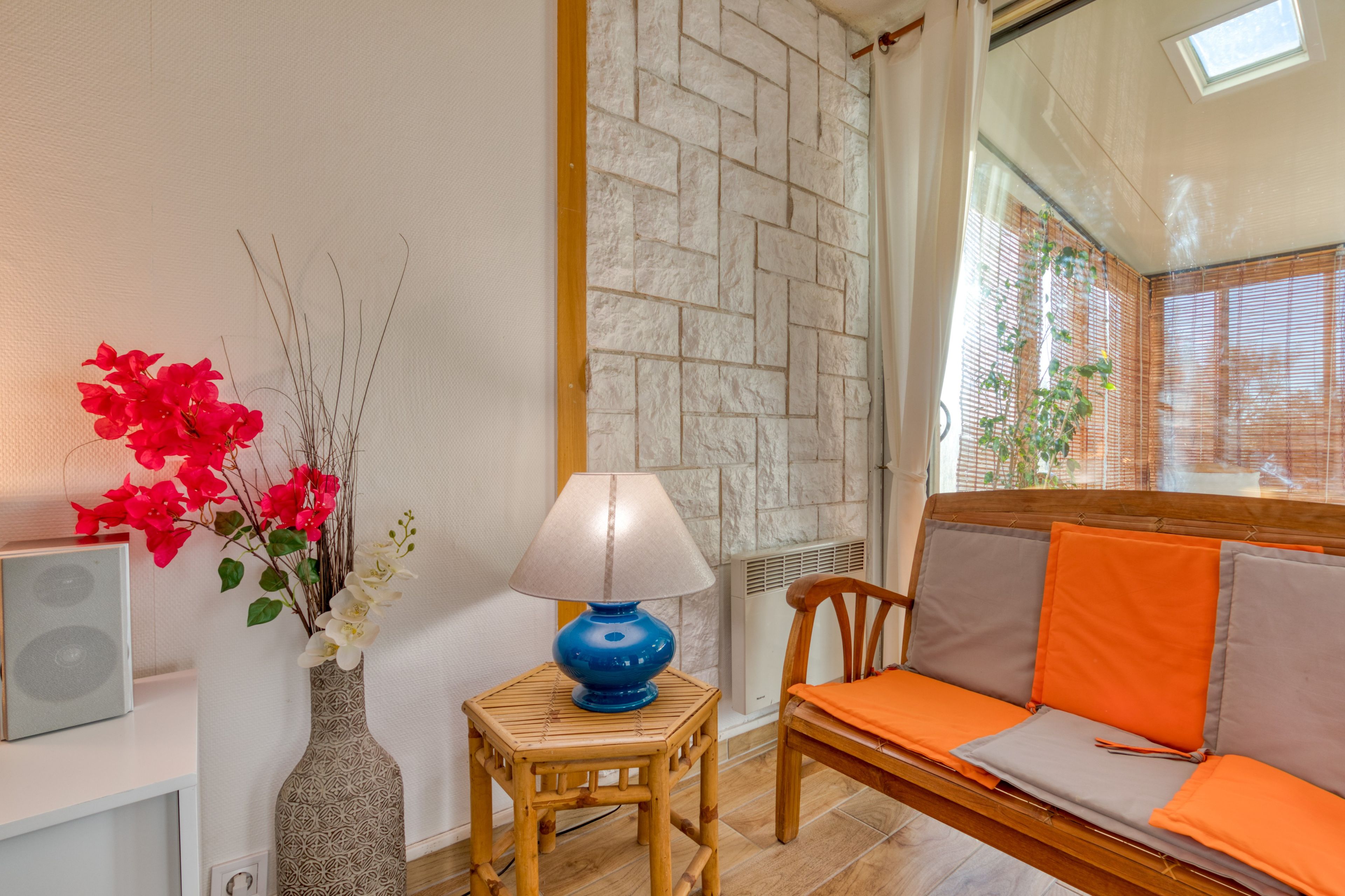 Ein Zimmer mit einer Couch, einem kleinen Tisch mit Lampe, einer dekorativen Vase mit Blumen und einer Wand mit Strukturmuster.