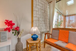 A room with a sofa, a small table with a lamp, a decorative vase with flowers, and a wall with a textured pattern. - By the Water...!!! 50 Meters from the Beach (Narbonne-Plage)