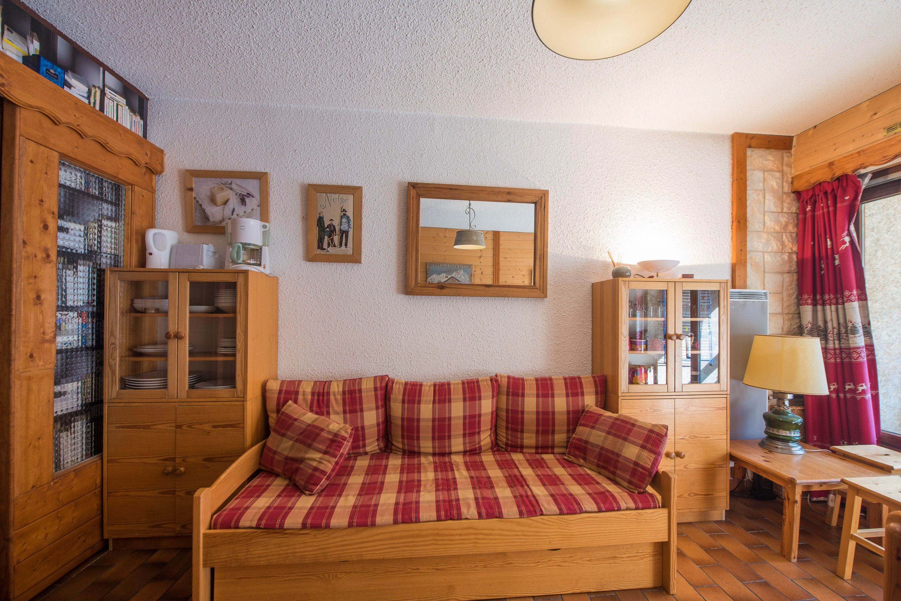 Ein gemütliches Zimmer mit einer Holzsofa, einem Schrank mit Glastüren und einem Spiegel an der Wand.