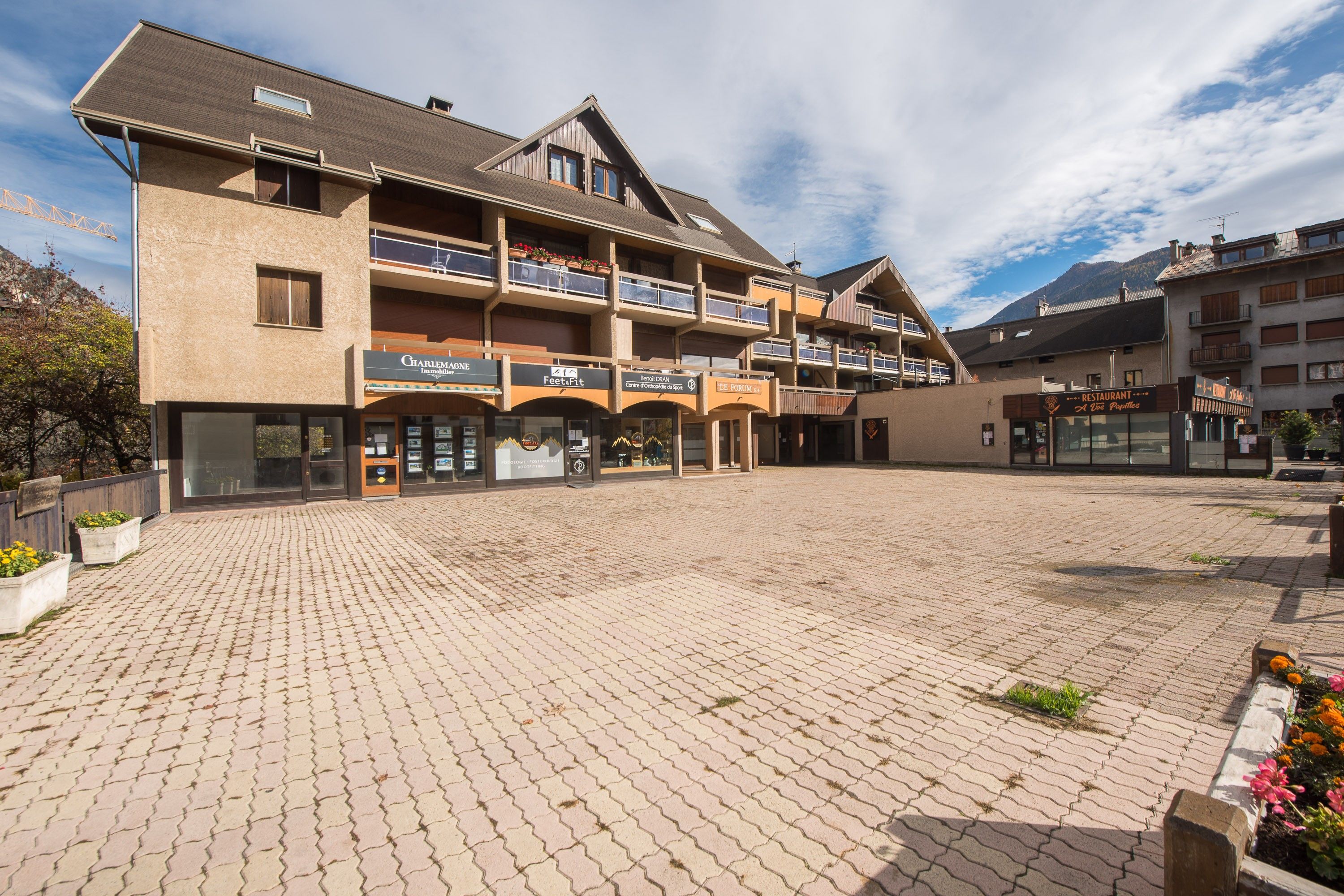 Ein mehrstöckiges Gebäude mit einem Erdgeschoss, das verschiedene Geschäfte und ein Restaurant beherbergt.
