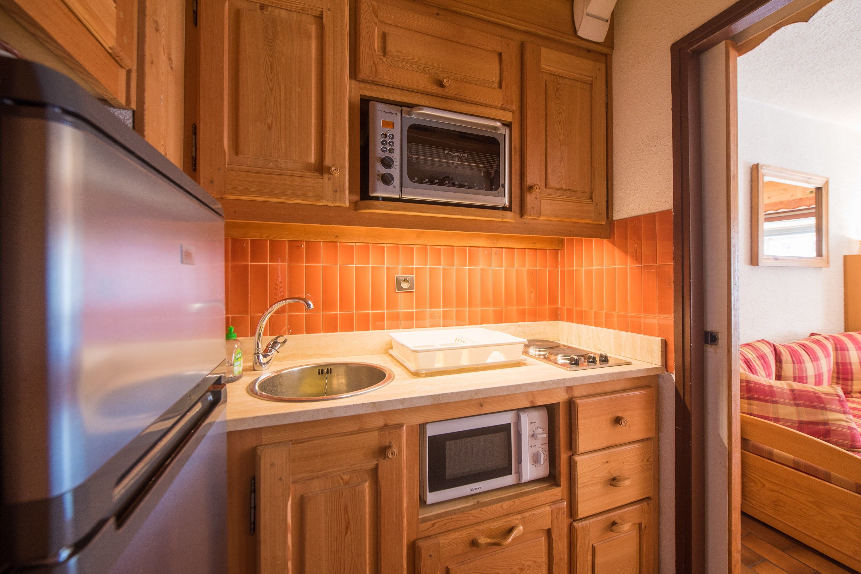 A compact kitchen with a refrigerator, microwave, and oven.
