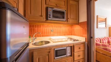 A compact kitchen with a refrigerator, microwave, and oven.
