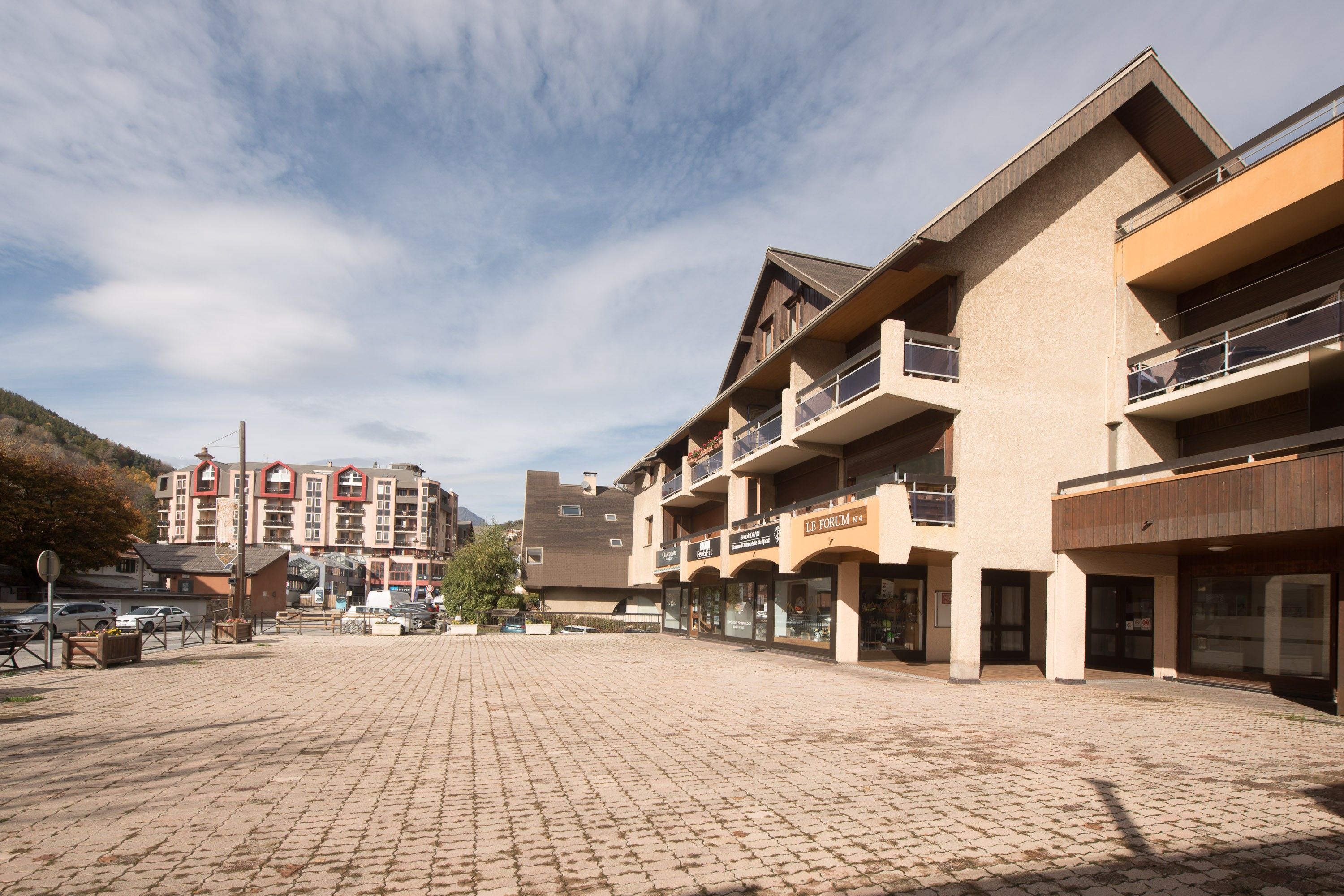 A paved square with buildings, balconies, and storefronts.