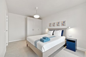 A bedroom with a bed, bedside tables, a wardrobe, and artwork on the wall. - Blue Horizon apartment in Marina Palace (Adeje)