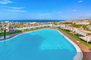 A swimming pool with a view of the sea, surrounded by lounge chairs and umbrellas. - Island Village Paradise apartment (Costa Adeje)