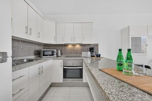 A modern kitchen with white cabinetry, a built-in oven, a microwave, and a coffee maker. - Island Village Paradise apartment (Costa Adeje)