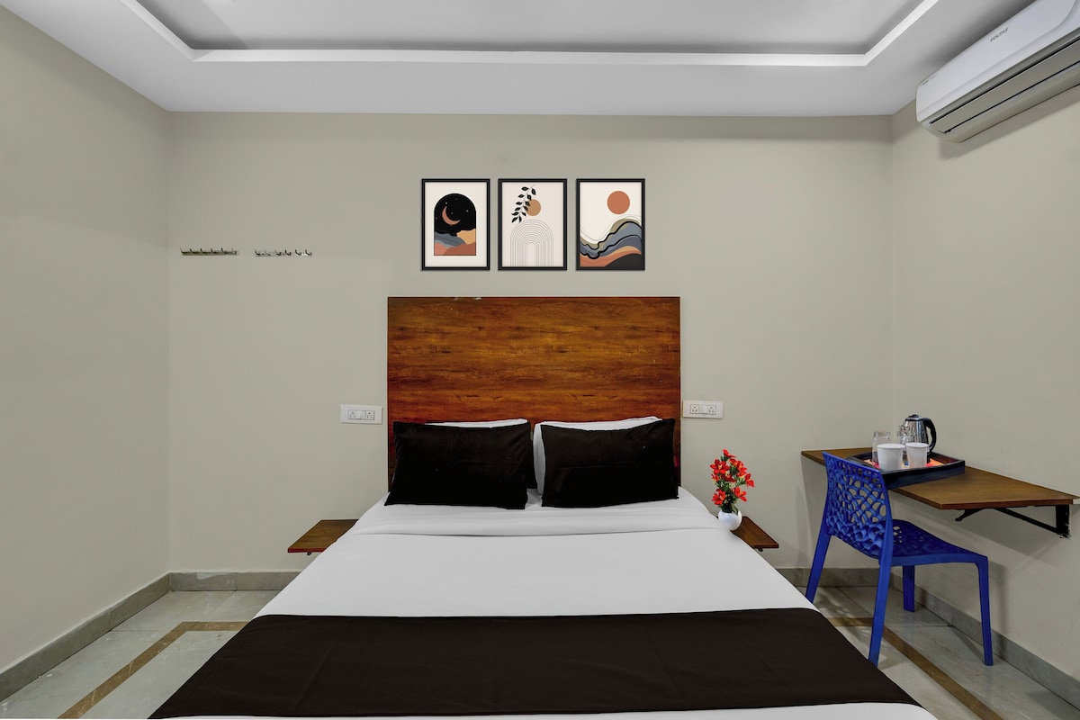 Habitación de hotel con una cama, una mesita de noche, un escritorio y tres obras de arte enmarcadas en la pared.