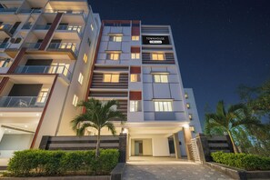 Un hotel de varios pisos con diseño moderno, que cuenta con balcones, una entrada bien iluminada y un letrero que indica que es administrado por OYO.