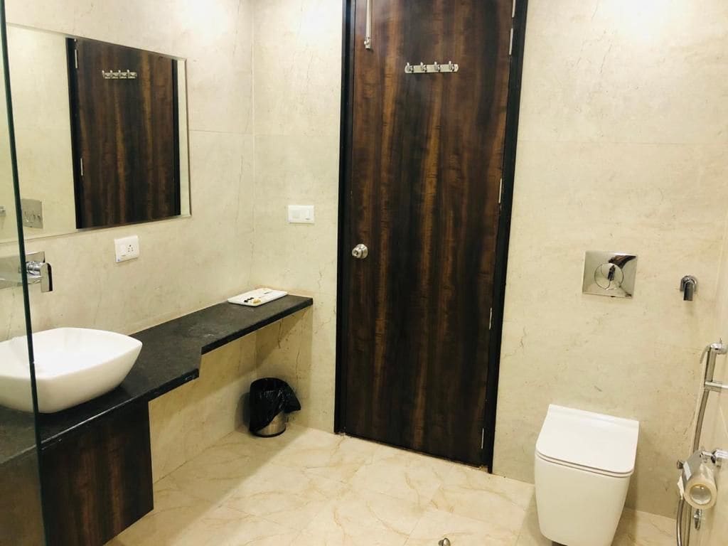Un bany amb un lavabo blanc, una porta de fusta fosc i un vàter.