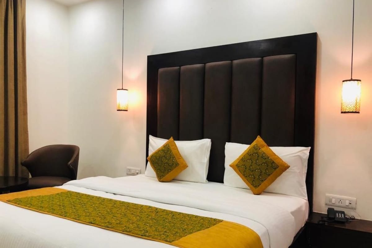 A hotel room with a large bed, two bedside lamps, a chair, and a nightstand.