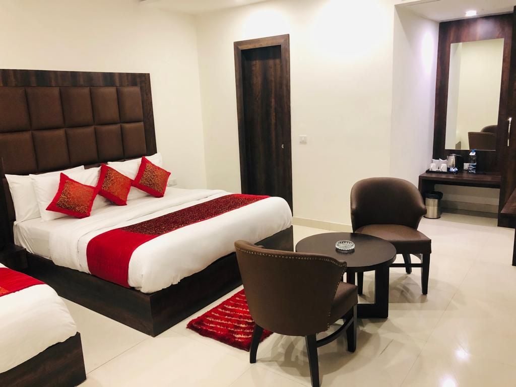 Habitació d'hotel amb un llit gran, dues cadires, una taula petita i un mirall.
