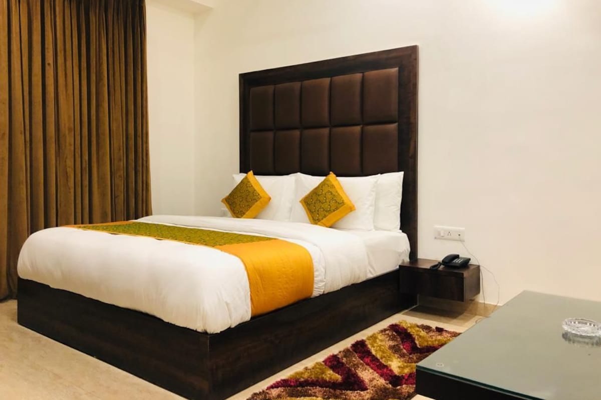 A hotel room with a large bed, a headboard, a nightstand, and a small table.