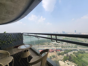 A balcony with a glass table and chairs, overlooking a cityscape with buildings and a river. - Vinis Cloud Stay (New Delhi)
