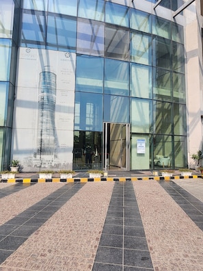 A modern building with a glass facade, a prominent entrance, and a landscaped area with potted plants. - Vinis Cloud Stay (New Delhi)