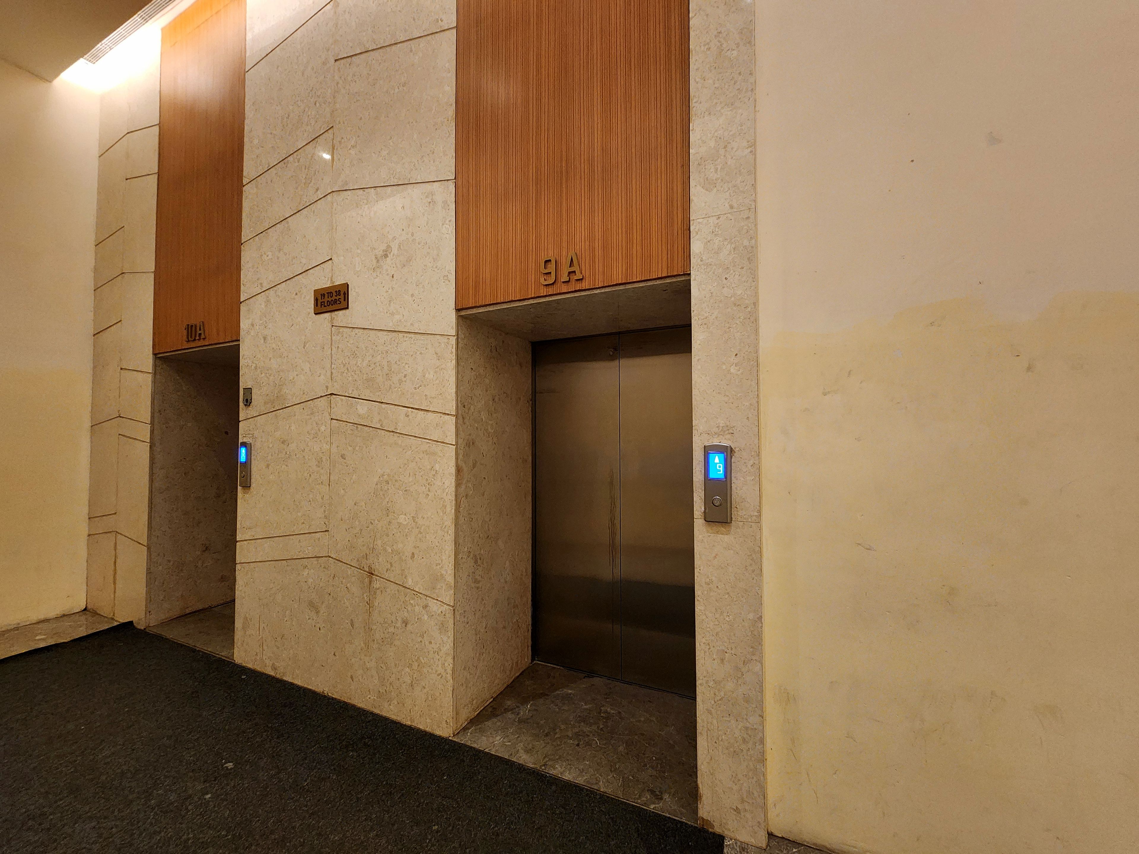 An elevator with a digital display, a wooden panel above it, and a sign indicating the floor number.