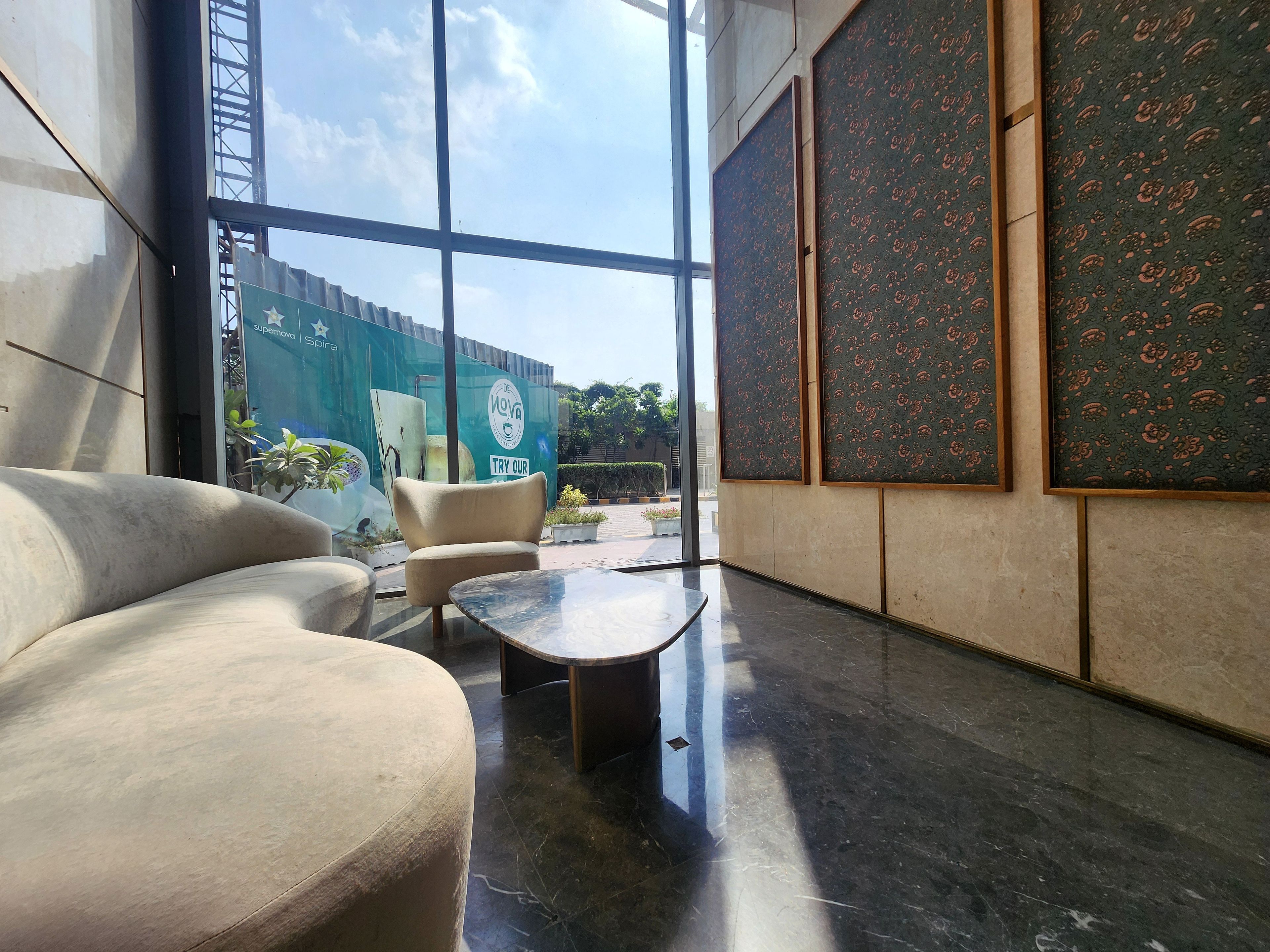 Un interior moderno con un sofá curvo, una mesita y ventanas amplias con vistas al exterior.