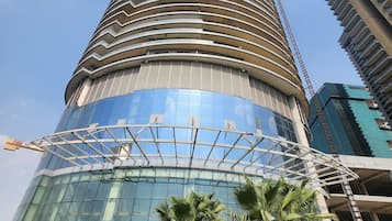 Un edificio moderno de forma cilíndrica, con amplios ventanales de vidrio y un área ajardinada circundante con palmeras.