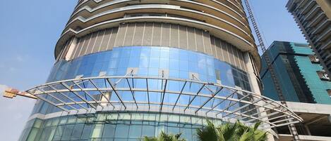 A modern building with a cylindrical shape, large glass windows, and a surrounding landscaped area with palm trees.