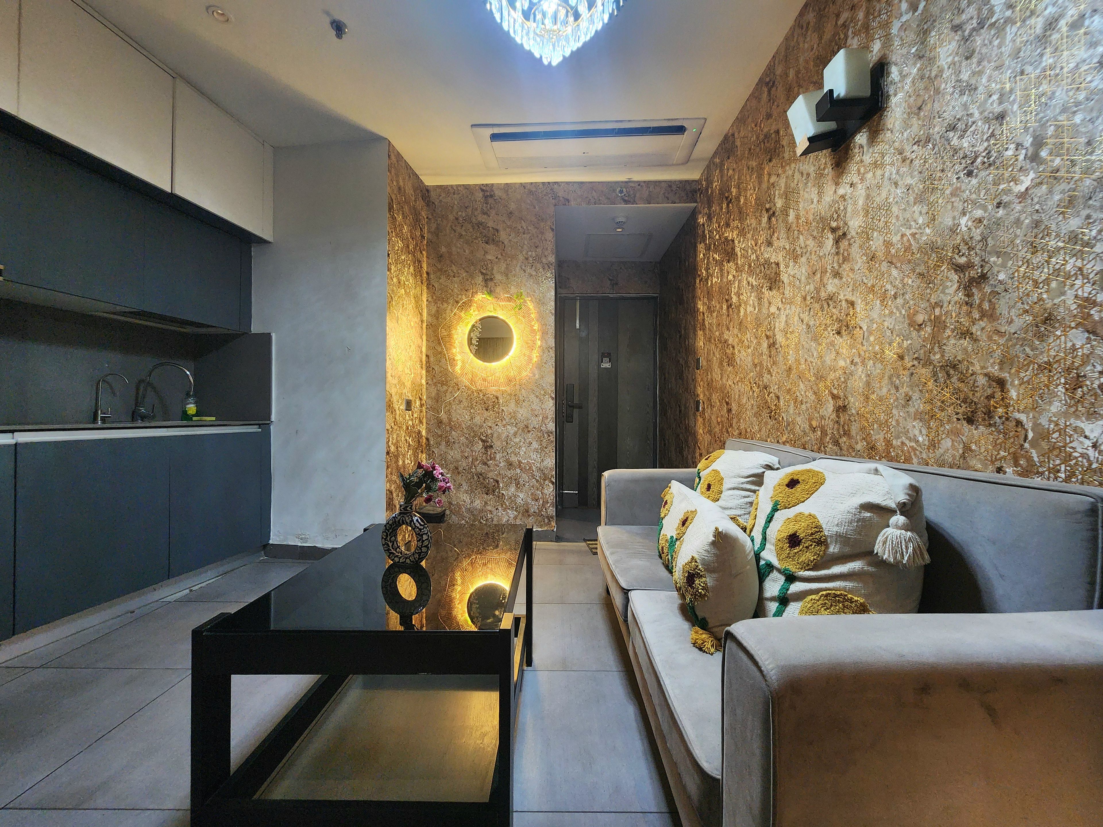A modern living room with a sofa, a coffee table, and a kitchen area with cabinets and a sink.