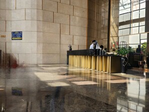 A hotel reception area with a marble floor, a reception desk, and a large window. - Vinis Cloud Stay  (Delhi)
