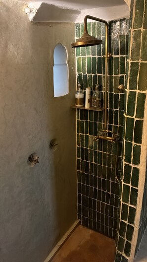 Ein Badezimmer mit Dusche, kleinem Fenster und gefliesten Wänden.
