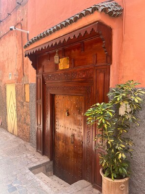 Une porte en bois ornée de sculptures complexes et une plaque métallique fixée au-dessus.