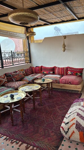 Un intérieur marocain traditionnel avec un canapé à motifs, une table basse en bois et une lanterne suspendue.