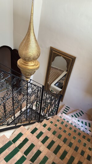 Un escalier avec un revêtement de sol à motifs, une rampe en métal et une lampe décorative.