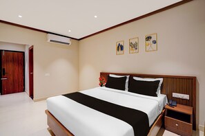 Ein Hotelzimmer mit einem großen Bett, Nachttischen, einer Klimaanlage und Wandbildern.