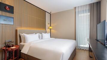 A hotel room with a large bed, a desk, a television, and a wall-mounted telephone.