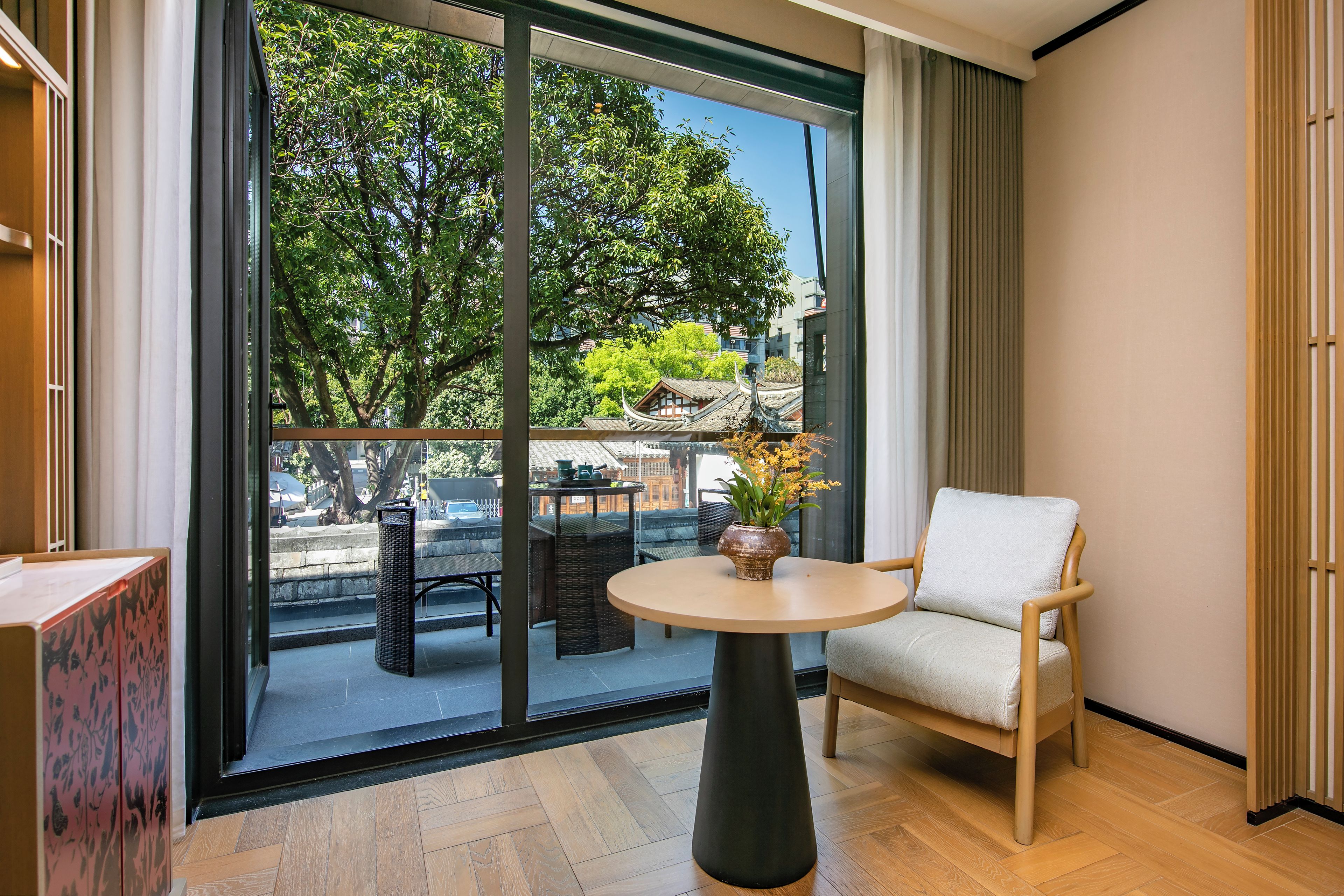 A modern room with a balcony, a round table, a chair, and a potted plant.
