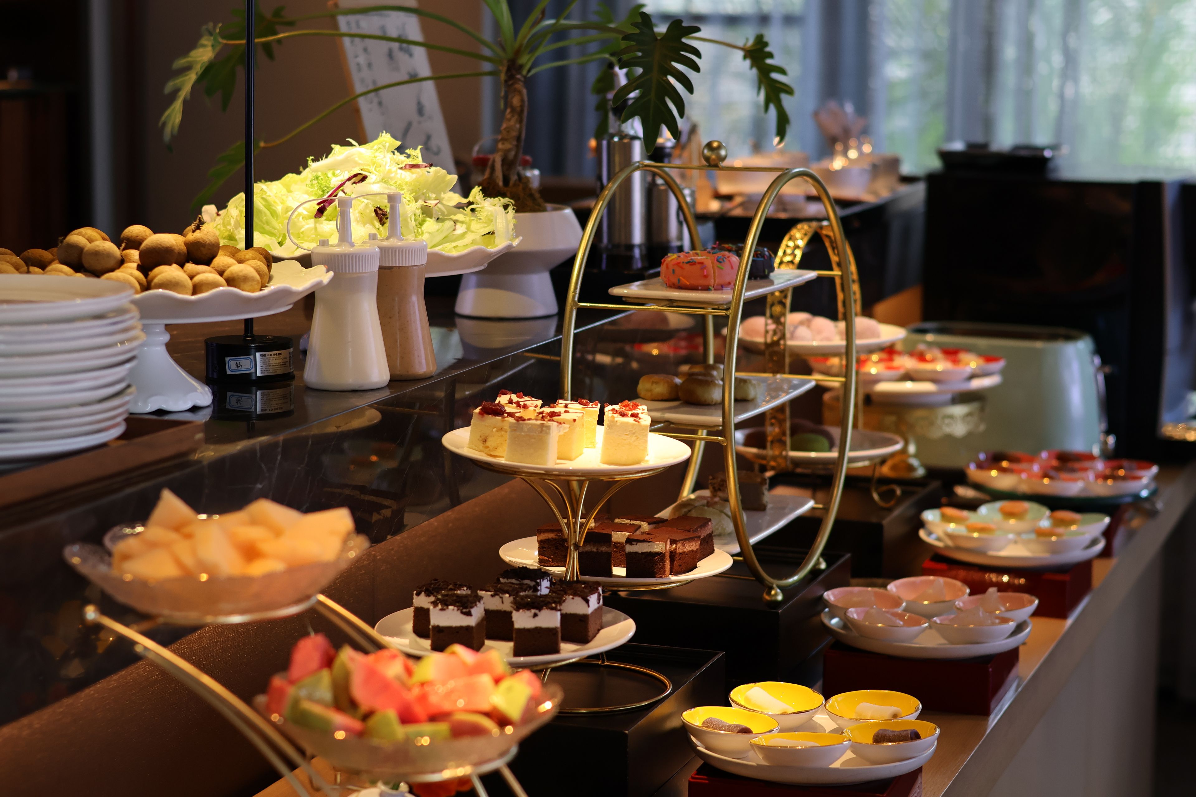 A buffet with various food items and a three-tiered dessert stand.
