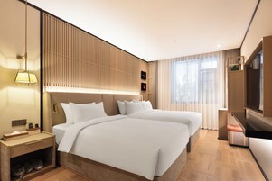 Habitación de hotel moderna con una cama grande, mesitas de noche, televisor y vistas al exterior.