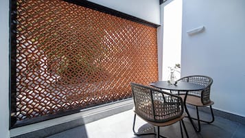 Une pièce avec un paravent à motifs, deux fauteuils en osier et une petite table.