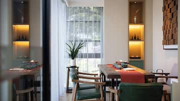 Un área de comedor con mesa de madera, sillas y una planta en maceta.