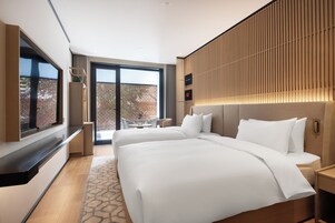 Una habitación de hotel moderna con una cama grande, televisión y balcón con vistas.